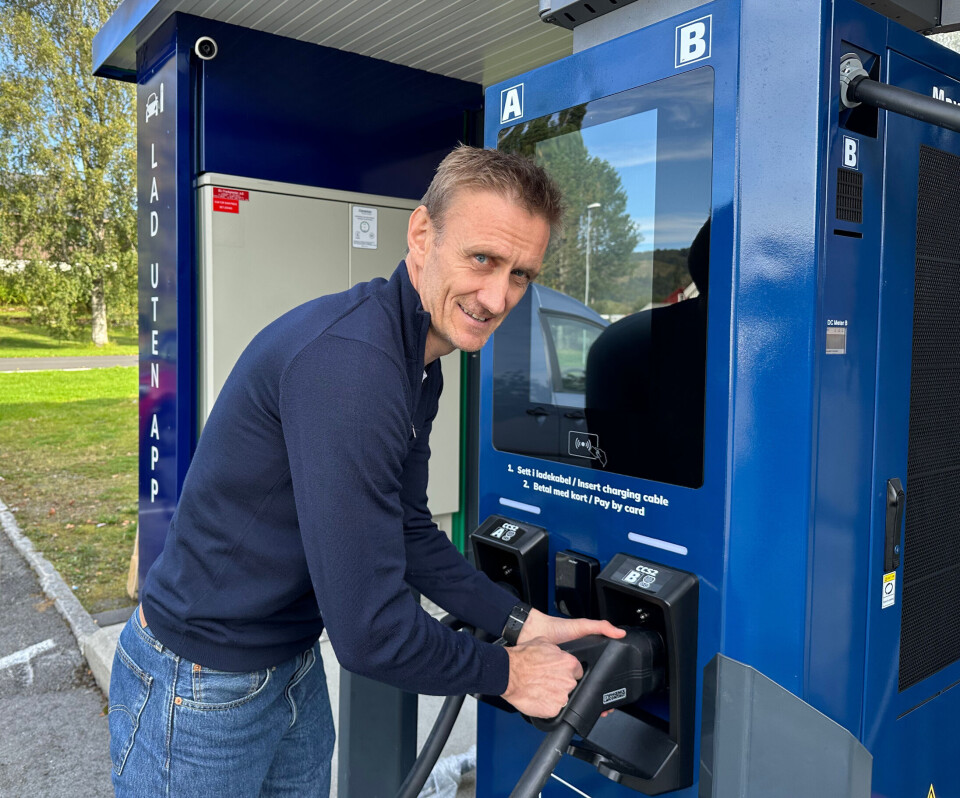 Håkon Solvik tester den nye ladestasjonen i Rindal sentrum. En mann som står med handa på en elbillader på en ladestasjon.