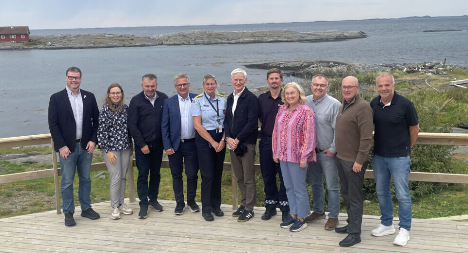 Ringholmen Sjøhus i Aure, fra venstre: Henning Torset, ordfører Aure, Ingrid Waagen Rimstad, ordfører Tingvoll, Knut Sjømæling, ordfører Gjemnes, Svein Roksvåg, ordfører Smøla, Eva Strømskag, distriktssjefsjef sivilforsvaret, Ole Jan Tønnesen, fylkesveidirektør, Nikolai Tallaksen, sivilforsvarsadjutant, Ingrid O. Rangønes, ordfører Averøy, Hugo Pedersen, ordfører Surnadal, Ståle Refstie, ordfører Sunndal og Kjell Neergaard, ordfører Kristiansund En gruppe mennesker står på en terrasse foran fjorden.  Et nes midt i fjorden.