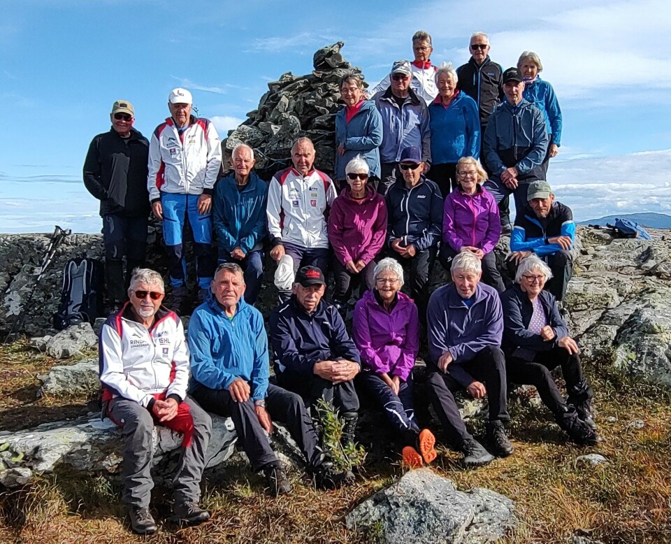 Ved varden på Tifjellet. Ei gruppe med friluftskledde folk som har samlet seg for fotografering ved en varde.