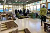 Flere personer inne i et skolelokale for byggfag, med en del halvferdige bygningselementer på gulvet.