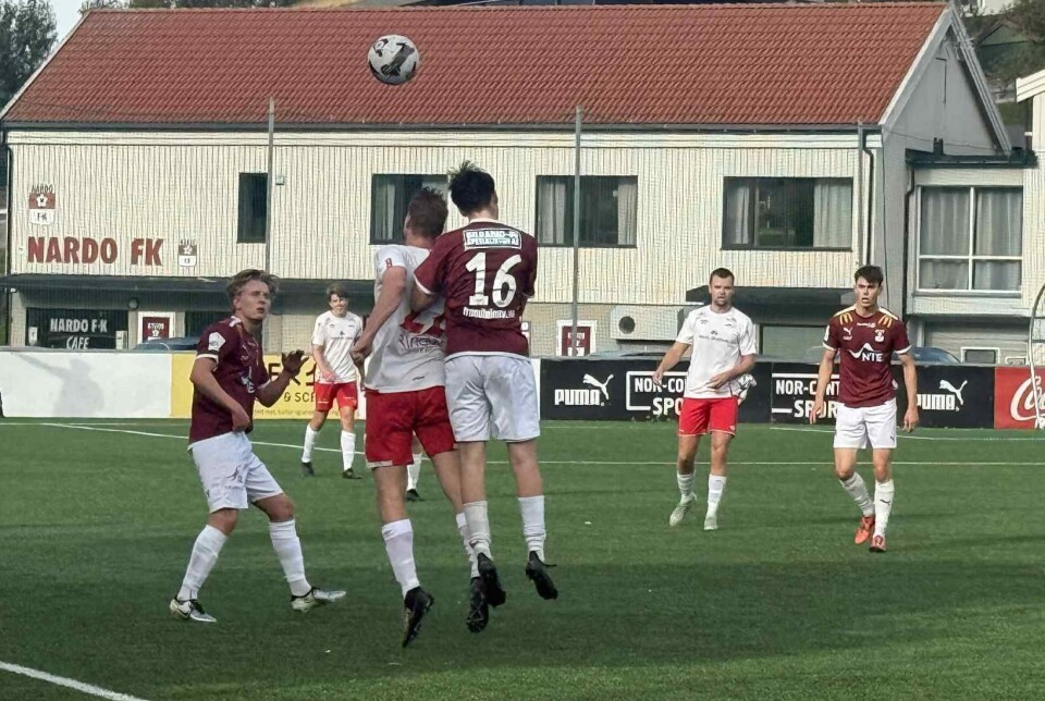 Nedtur mot Nardo 2 Fotballspillere i hvite overdeler spiller mot spillere i vinrøde overdeler på en grønn kunstgressbane