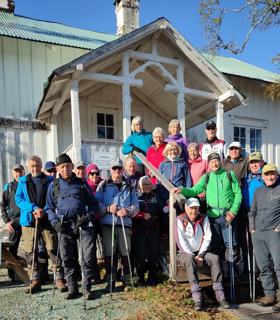 Ved direktørboligen. Ei stor gruppe turgåere oppstilt foran et gammelt trehus.