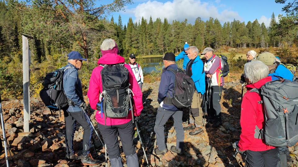Tirsdagstur til Dragsetgruva Ei gruppe med turkledde folk ved et vann i en skog i marka. Høstvær og sol.