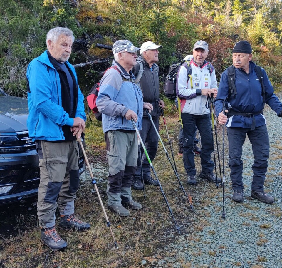 Litt orientering om Dragsetgruva på parkeringsplassen før vi begynner på runden. Ola Løset var med og guidet. Fem turkledde menn med gåstaver på en parkeringsplas.