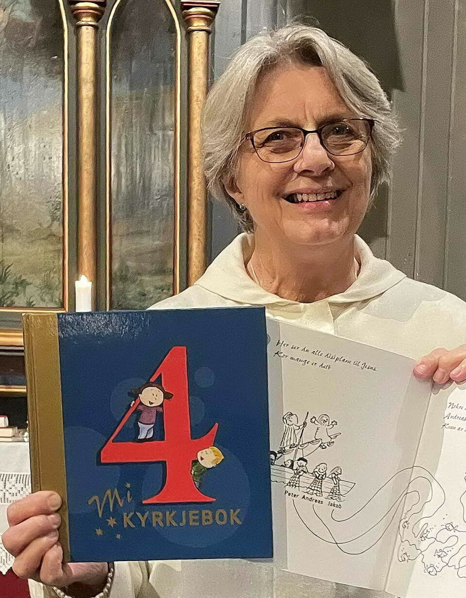 - Denne boka får 4-åringane søndag 5. oktober, seier Randi Bøe. På kyrkjekvelden tysdag fortel ho litt om boka og arbeidsheftet som følgjer med. Ei smilende dame med briller og kort grått hår, som holder fram ei bok. På framsida står tallet 4, og 'Mi kyrkjebok'.