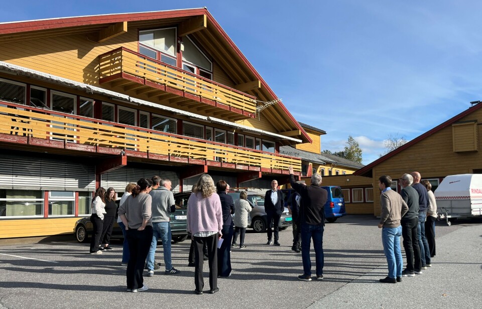 Kommunestyret fikk omvisning på Rindal helsetun. Flere personer som står og prater utenfor et stort bygg.
