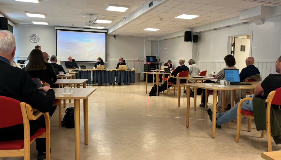 Mindreforbruk etter andre tertial Et møte der deltakerne sitter på rekker på små bord, foran en storskjerm.