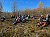 Ei gruppe med flere turgåere som har tatt en rast på fjellet. Høstfarger, sol og skyfri himmel.