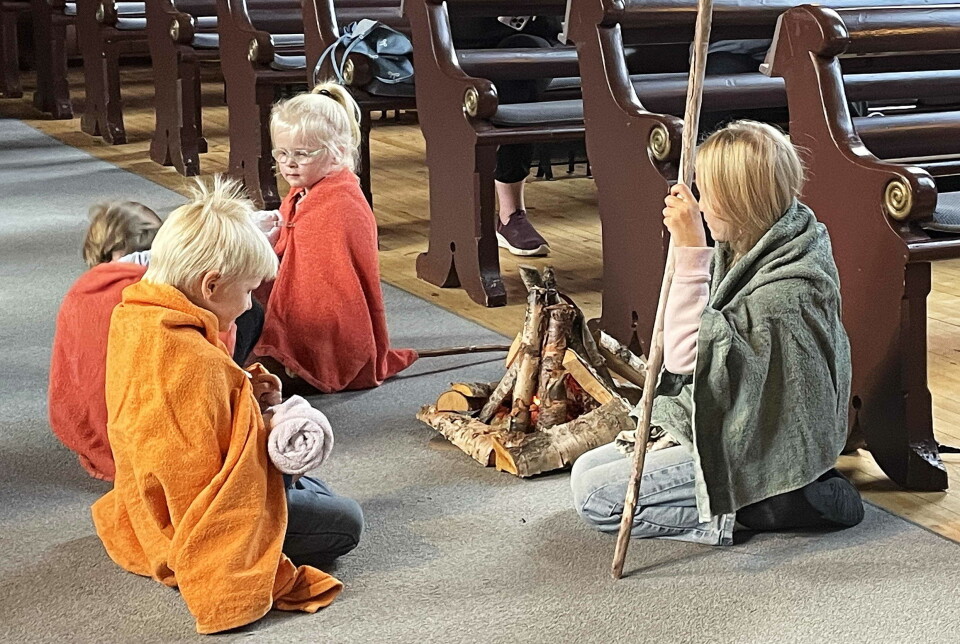 Gjetarane samla ved bålet nede i kyrkja. Fire barn ukledd som gjetere, og noe som skal forestille et bål på midtgangen i ei kirke.