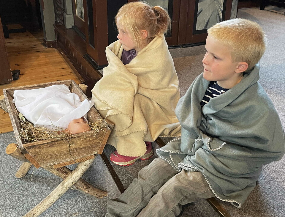Maria og Josef passa krybbebarnet. To barn, ei hente og en gutt, men fleecepledd rundt seg. De sitter foran ei 'krybbe' med ei babydukke oppi.