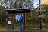 En turgåer som står og ser på ei informasjonstavle. Høstfarger, sol og lettskyet himmel.
