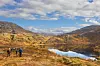 Ei gruppe turgåere ved et vann på fjellet. Høstfarger, sol og lettskyet himmel.