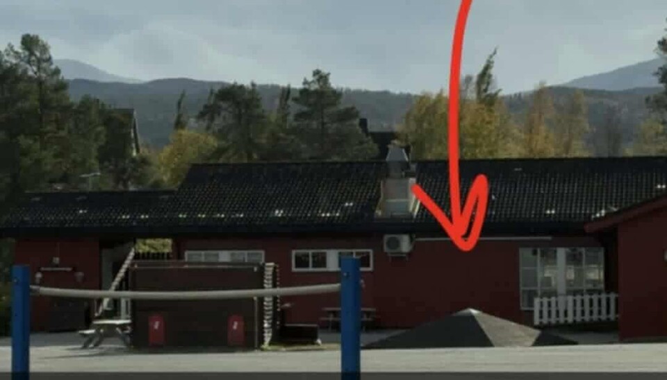 Her ser man paviljongen, og det avblåste taket. Bildet viser en skolebygning med en paviljong uten tak. Det er en rød pil ned mot hvor taket ligger, som er ved siden av paviljongen.