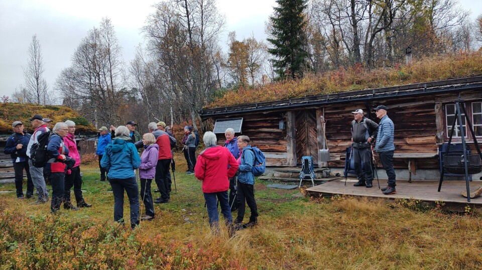Sesongens siste tirsdagstur gikk til Gammelseterøyan Ei stor gruppe med turgåere mellom to gamle tømmerhus i marka.