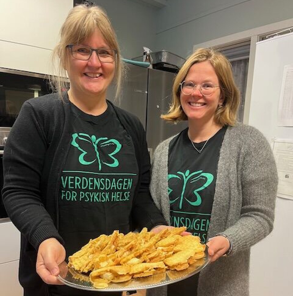 Marit S Meisingset og Siv Torvik byr på bakels på den lokale markeringen av verdendagen for psykisk helse. To smilende damer som holder fram et stort fat med vafler. Begge har t-skjorte med logo og påskrift 'Verdensdagen for psykisk helse'.