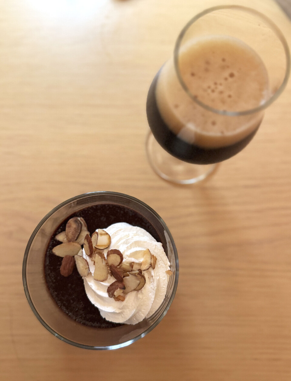 Dessert til ølsmakingen. En dessertporsjon med krem og skivede mandler på toppen, sammen med et glass med mørkt øl.