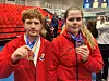 En gutt og ejnte i røde treningsklær viser frem hver sin medalje