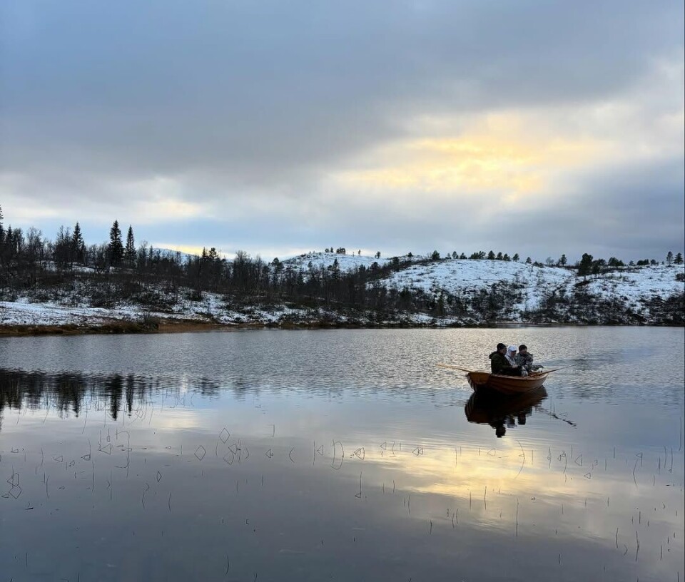 Snaushelg En liten robåt på et vann på fjellet, med et par personer oppi. Det er nysnø rundt vannet.