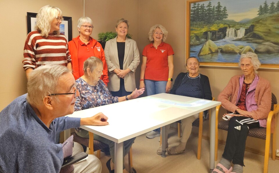 Jenny Nordheim, Surnadal Sjukeheim, Mary-Ann F. Fiske, Surnadal Demensforening og helselag, Mette Helen Mikkelsen, Tinde Sparebank og Liv Botten, Surnadal Demensforening og helselag. Fornøyde motttakere, brukere og givere. Fire sykehjemspasienter rundt et bord, og bak står fire smilende damer ved siden av hverandre.