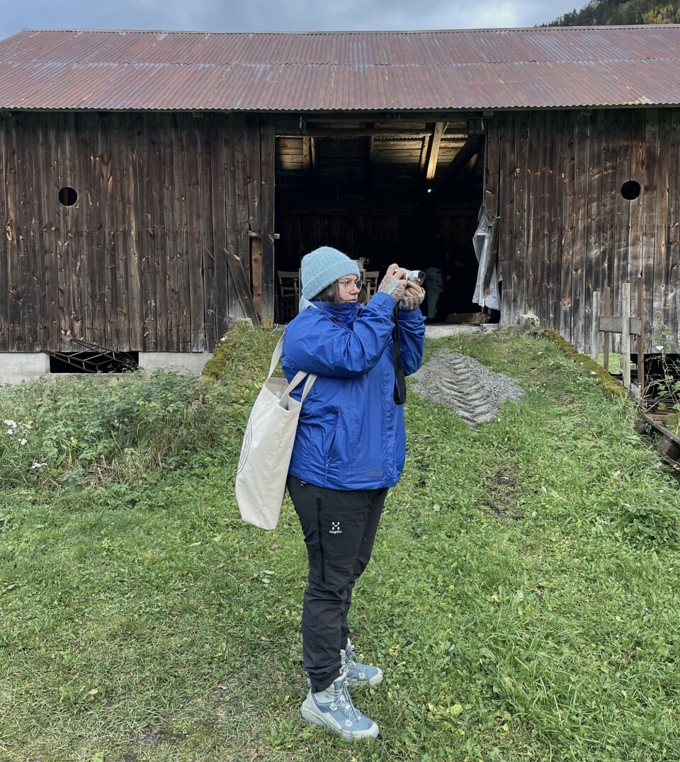 Ytre Kunstfagskule ønskjer å utdanne kunstnarar som vågar å stille spørsmål ved eigne perspektiv, og som kan kaste nytt lys over omgjevnadene dei er ein del av. Ei godt kledd dame som står utenfor en gammel låve og fotograferer.