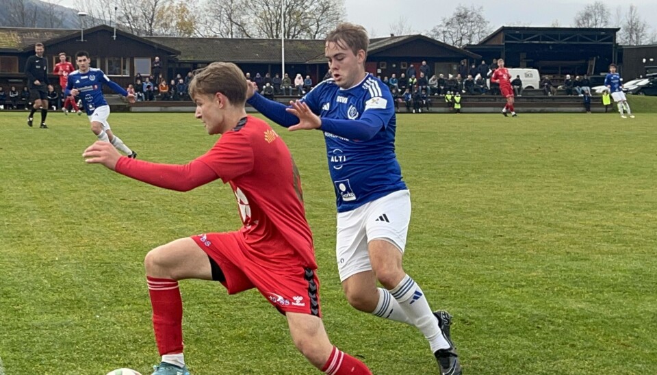 Surnadal måtte se seg slått av Spjelkavik. to fotballspillere på bane, en med rød drakt og en med blå