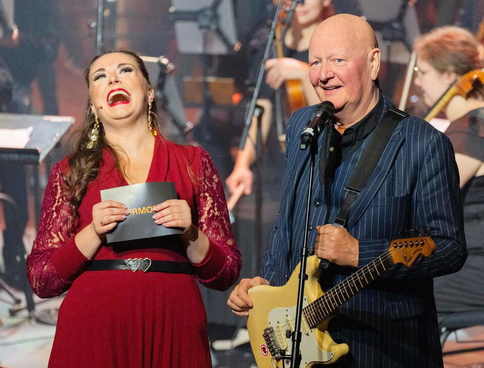 – Kultursentra på Nordmøre er Bøfjorden og Kristiansund, skøya Frode Alnæs under opninga av Normoria – til stor jubel hos salen og hos konferansier (og songsolist) Sigrid Bøe. Ei dame og en mann med gitar på en scene.