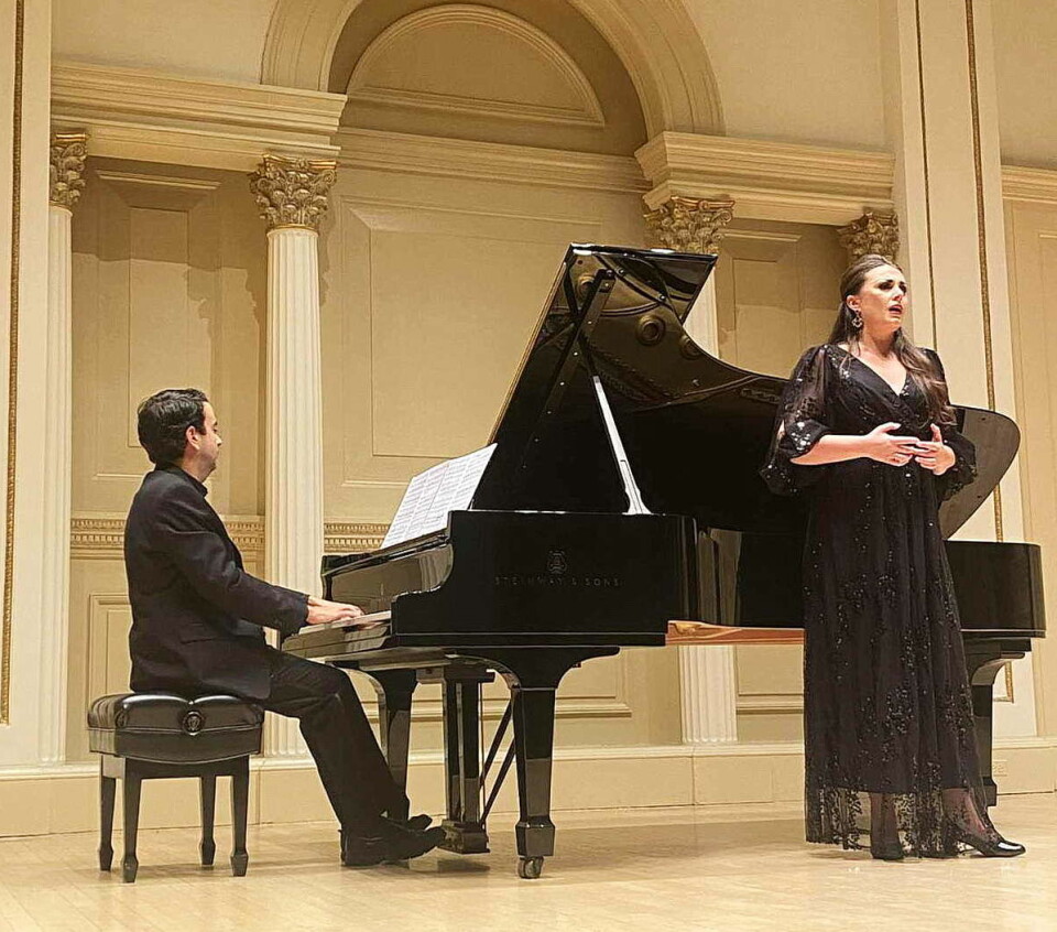 Vinnarkonserten i Carnegie Hall: Sigrid framførte operamusikk av Puccini, Verdi og Lehar. Ei operasangerinne i svart kjole som står og synger ved et flygel, der en dresskledd mann sitter og spiller.