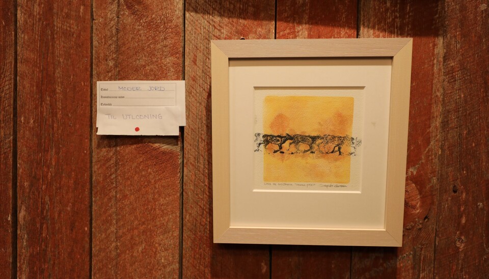 Rindal kunstlag holder utlodning der premien er dette bilde laget av kunstneren. Lite bilde med gulorange bakgrunn og trykk med flere drektige reinsdyr på rekke.