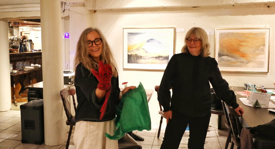 Leder i Rindal kunstlag, Mie Sandø, ønsket publikum og kunstner velkommen og overrakte rindalsvotter fra Rindal skimuseum i velkomstgave til kunstner Inger Kristin Gorseth. Kunstneren prøver på en av de røde og svarte strikkavottene mens leder ser på