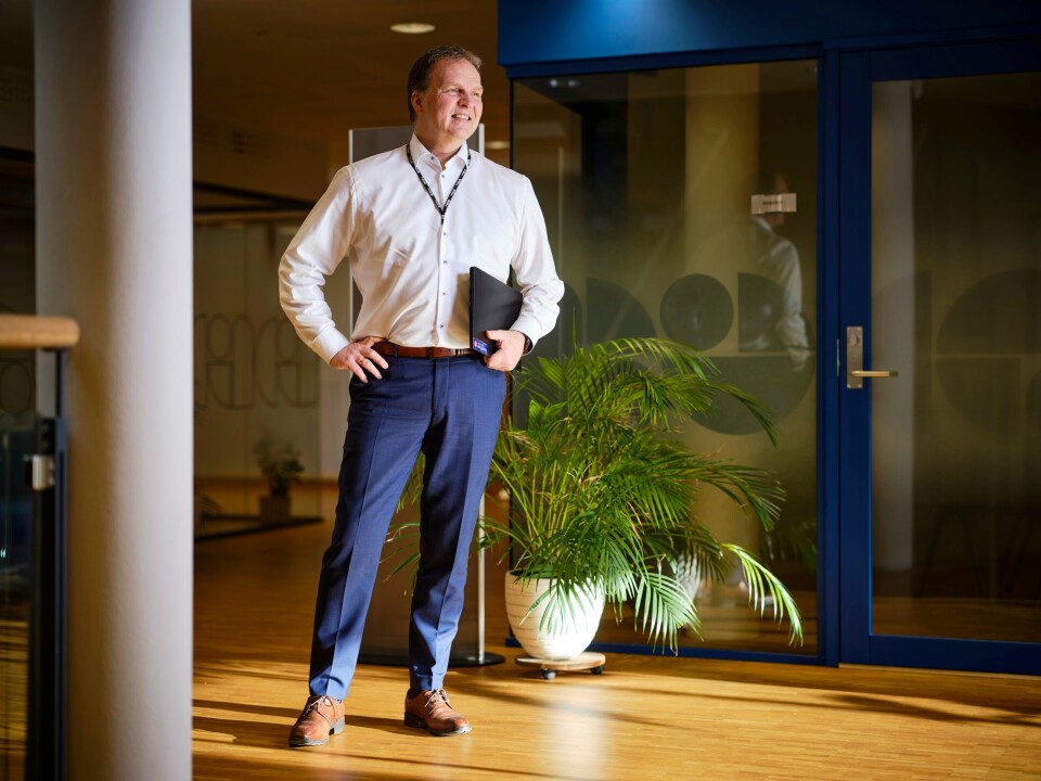 Administrerende direktør Allan Troelsen. En smilende mann i hvit skjorte, som står med ei dokumentmappe under armen.