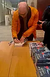 En mann som signerer bøker.