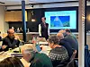 Flere personer rundt et bord i et møterom.