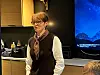 Ei dame med mørkt kort hår og briller, og skjerf rundt halsen, som snakker til ei forsamling.