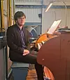 En organist som sitter ved et kirkeorgel.