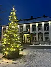 Et utendørs juletre foran en gammel trebygning i skuringen.
