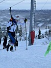 Mann med ski på ryggen løper opp en snødekt bakke