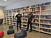 To personer foran store bokhyller i et lyst bibliotek med lave stoler.