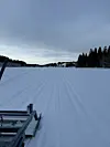 Nypreparerte skispor på snødekt innsjø omgitt av skog