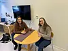 To kvinner sitter ved et rundt bord på et kontor.