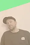 Mann med caps foran lys vegg med grønt diagonalt felt øverst