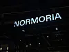 Normoria-skilt lyser på en bygning om kvelden.