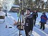 Folk rundt bålstativ og grill i solfylt vinterlandskap med snø og skog