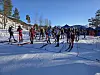 Randoneeløpere står klare ved startstreken på et snødekt stadion i fjellterreng.