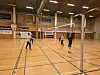 Voksne som spiller volleyball i en stor innendørs idrettshall.