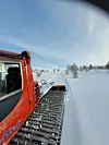 Rød PistenBully-løypemaskin som preparerer skispor i snødekt fjellterreng