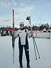Langrennsløper holder Madshus-ski og staver på snødekt skistadion.