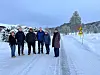 En gruppe mennesker står på en snødekt vei i vinterlandskap.