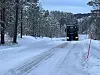 Lastebil på snødekt mal vei med brøytestikker langs veikanten.