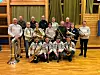 Gruppebilde av brassmusikere med instrumenter i en gymsal.