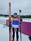 Langrennsløper med Madshus-ski foran reklamebannere på snødekt skistadion.